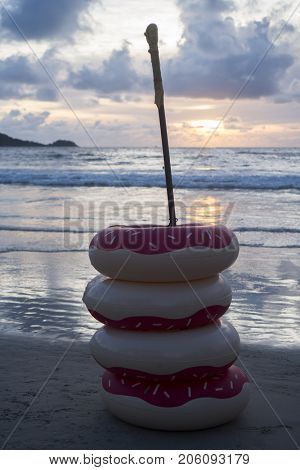 Pile of inflatable rings on the sandy beach isolated over beautiful sea and sunset sky background