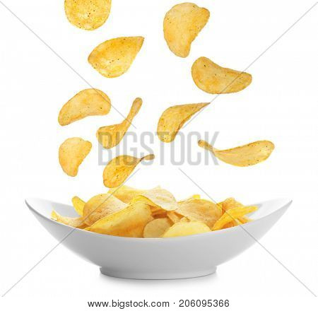 Tasty potato chips falling onto plate on white background