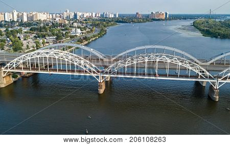 Aerial top view of automobile and railroad Darnitsky bridge across Dnieper river from above, Kiev (Kyiv) city skyline, Ukraine