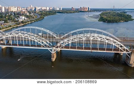 Aerial top view of automobile and railroad Darnitsky bridge across Dnieper river from above, Kiev (Kyiv) city skyline, Ukraine