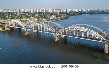 Aerial top view of automobile and railroad Darnitsky bridge across Dnieper river from above, Kiev (Kyiv) city skyline, Ukraine