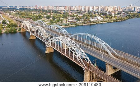 Aerial top view of automobile and railroad Darnitsky bridge across Dnieper river from above, Kiev (Kyiv) city skyline, Ukraine