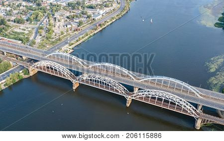 Aerial top view of automobile and railroad Darnitsky bridge across Dnieper river from above, Kiev (Kyiv) city skyline, Ukraine