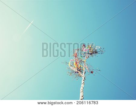 Looking up at may pole and aircraft on blue sky. European traditions. Photo filter.