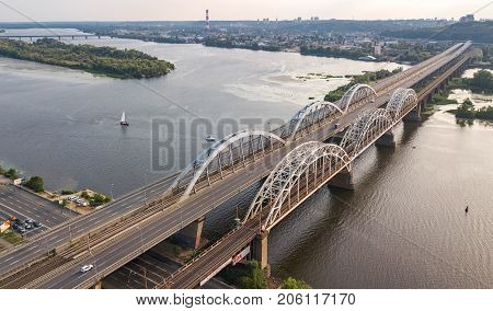 Aerial top view of automobile and railroad Darnitsky bridge across Dnieper river from above, Kiev (Kyiv) city sunset skyline, Ukraine