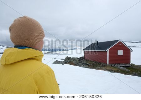 Man near typical norwegian red wooden house near famous Aurlandsvegen (Bjorgavegen) mountain road in Aurland, Norway in summer time