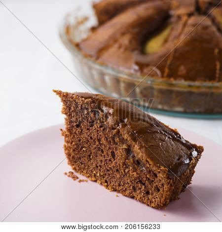 Slice of pear pie on pink plate with whole baked pie in background