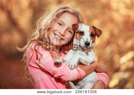 Child with dog at autumn. Happy girl with pet