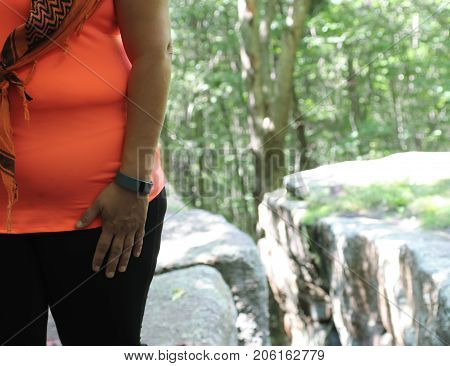 Out of shape woman walking in the woods with a fitbit