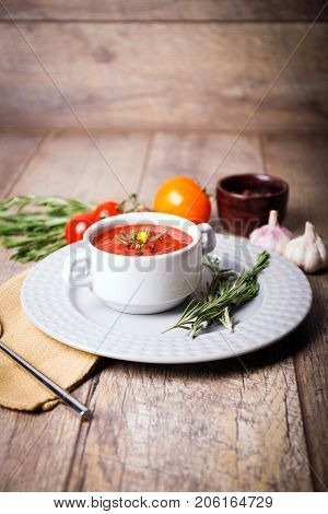 Red ukrainian borsch with two garlic, parsley and other different vegetables in a plate on a wooden table. Close-up of dish. Copy space. Food concept.