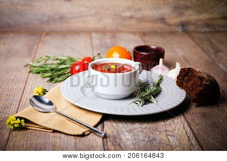Red ukrainian borsch with two garlic, parsley and other different vegetables in a plate on a wooden table. Close-up of dish. Copy space. Food concept.