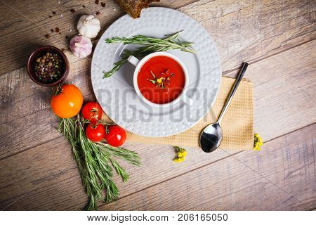 Red ukrainian borsch with two garlic, parsley and other different vegetables in a plate on a wooden table. Close-up of dish. Copy space. Food concept.