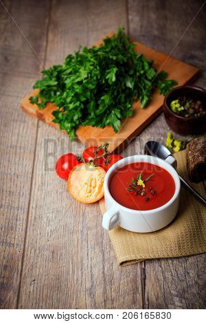 Red ukrainian borsch with sour, garlic, parsley, spices and a lot of dill and parsley on a wooden background. Copy space. Close-up of appetitzing dish. Food concept.