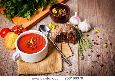 Red ukrainian borsch with sour, garlic, parsley, spices and a lot of dill and parsley on a wooden background. Copy space. Close-up of appetitzing dish. Food concept.