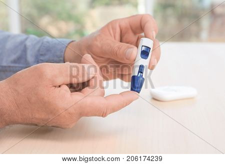 Man taking blood sample with lancet pen indoors