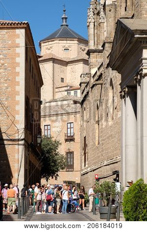 TOLEDO,SPAIN - AUGUST 8,2017 : Tourists on a narrow street next to the Cathedral in Toledo