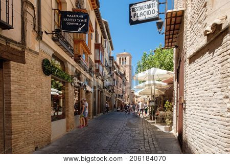 TOLEDO,SPAIN - AUGUST 8,2017 : Typical narrow street with restaurants and handicraft shops on the medieval city of Toledo in Spain