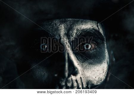 Close-up portrait of a man with a skull makeup dressed in a tail-coat and a top-hat. Baron Saturday. Baron Samedi. Dia de los muertos. Day of The Dead. Halloween.