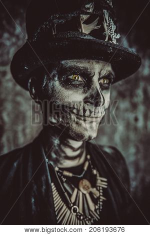 Close-up portrait of a man with a skull makeup dressed in a tail-coat and a top-hat. Baron Saturday. Baron Samedi. Dia de los muertos. Day of The Dead. Halloween.