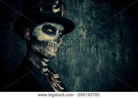 Close-up portrait of a man with a skull makeup dressed in a tail-coat and a top-hat. Baron Saturday. Baron Samedi. Dia de los muertos. Day of The Dead. Halloween.