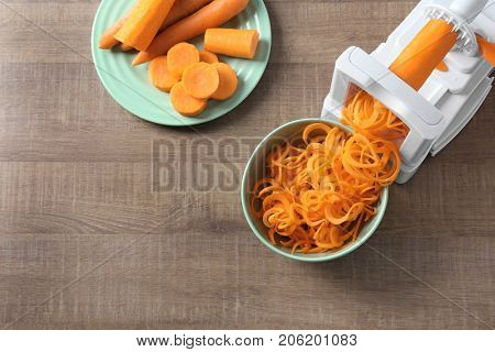 Spiral vegetable slicer with carrot spaghetti on table