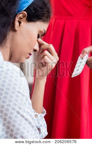 Woman giving to her young female friend medication against severe headache