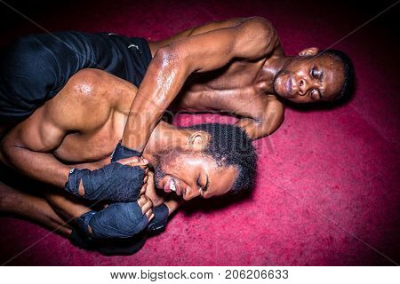 Two African American opponents struggling for dominance in ground fighting during MMA match