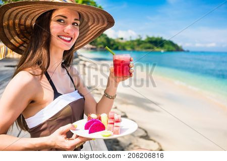 woman tourist at tropical beach eating fruit like water melon, pineapple and barbary fig for breakfast