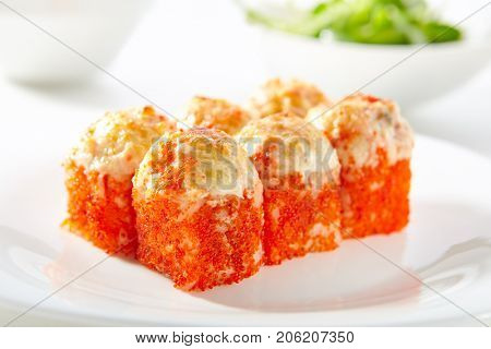 Hot Tobiko Maki Sushi - Sushi Roll Topped with Baked Cheese and Tobiko. Tobiko outside