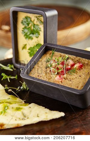 Menu of gastronomic restaurant. Cold appetizer - hummus of chick pea and eggplant pate with fresh herbs and pomegranate seeds on wooden round board