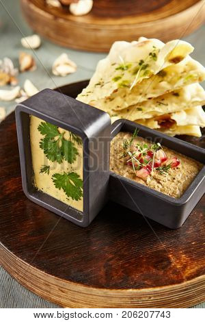 Menu of gastronomic restaurant. Cold appetizer - hummus of chick pea and eggplant pate with fresh herbs and pomegranate seeds on wooden round board