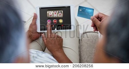 Slot machine with icons on mobile display against senior couple doing online shopping on digital tablet