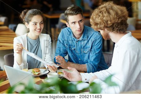 Multi-ethnic group of talented interior designers presenting ideas concerning joint project to their bearded client while having meeting at cozy restaurant