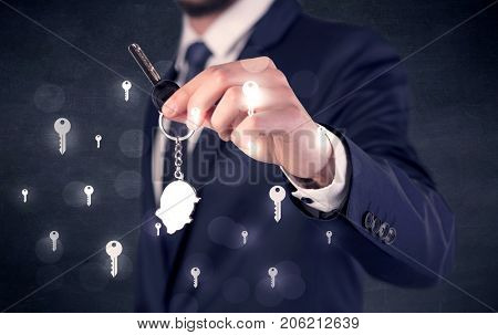 Businessman in suit holding keys with keys graphics around and dark background