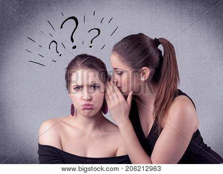 A teenager girl looking confused with drawn question marks above the head, while a girlfriend whispers something in her ear concept.