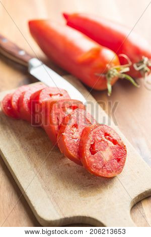 Sliced San marzano tomatoes on cutting board.