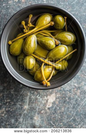 Pickled caper berries in bowl on kitchen table.