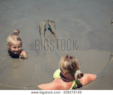 Mother gently bathing my daughter in the mud. Treatment non-traditional methods.