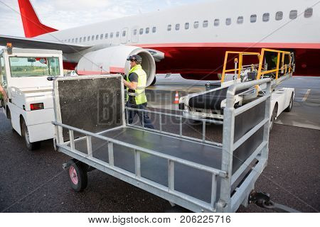 Worker Walking Between Truck And Airplane On Runway