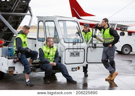Male Workers Communicating At Gangway On Wet Runway