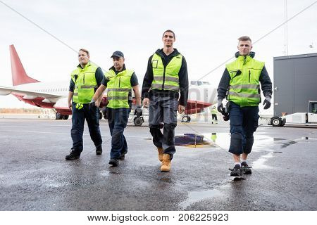 Full Length Of Workers Walking On Wet Runway