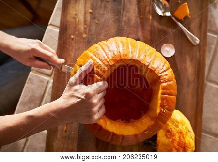 top down view of a woman carving a pumpkin in ktichen