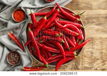 Plate with red chili peppers on wooden table
