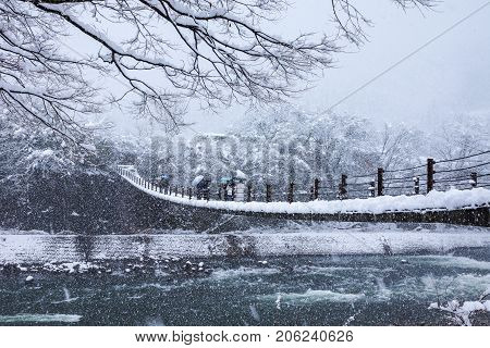 Gifu Japan - December 12 2013: Tourists walking on wooden bridge in Shirakawago world heritage village the toutist destination in winter with snow falling in Gifu Japan
