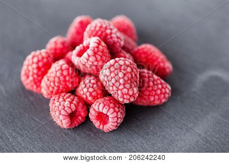 frozen raspberries on dark background - fruits and vegetables