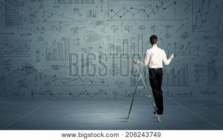 A businessman in modern stylish elegant suit standing on a small ladder and drawing pie and block charts on grey wall background with exponential progressing curves, lines, circles, , blocks, numbers