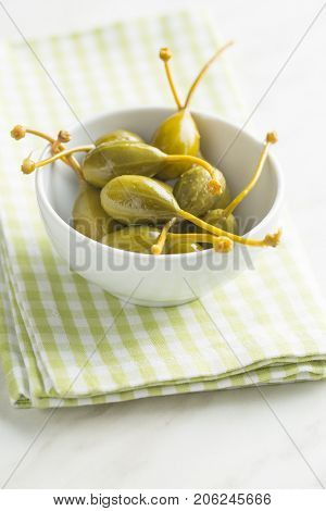 Pickled caper berries on kitchen table.