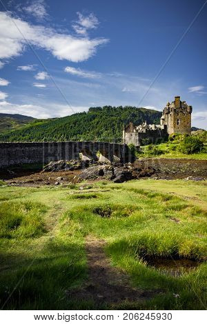 Gorgeous sun kissed vertical view of Eilean Donan Castle on a bright summer's day.