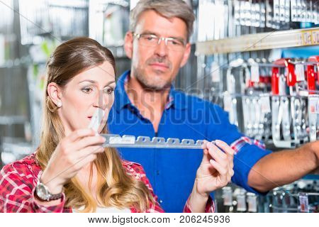 Employee of hardware store helping customer in ironware department with fittings