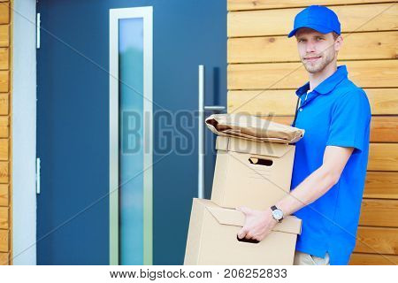 Smiling delivery man in blue uniform delivering parcel box to recipient - courier service concept. Smiling delivery man in blue uniform
